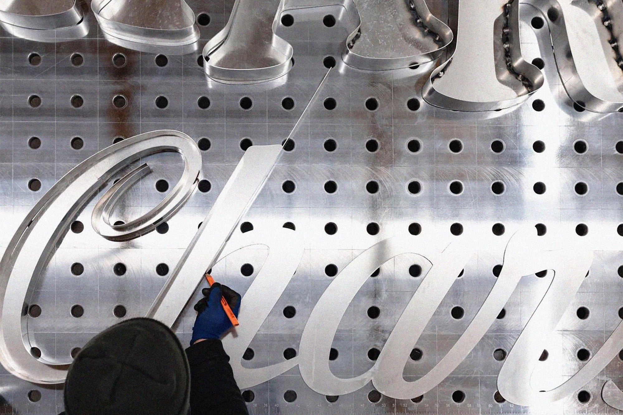 A sign fabricator cutting letters for a large scale sign of the Harry’s Charbroiled wordmark